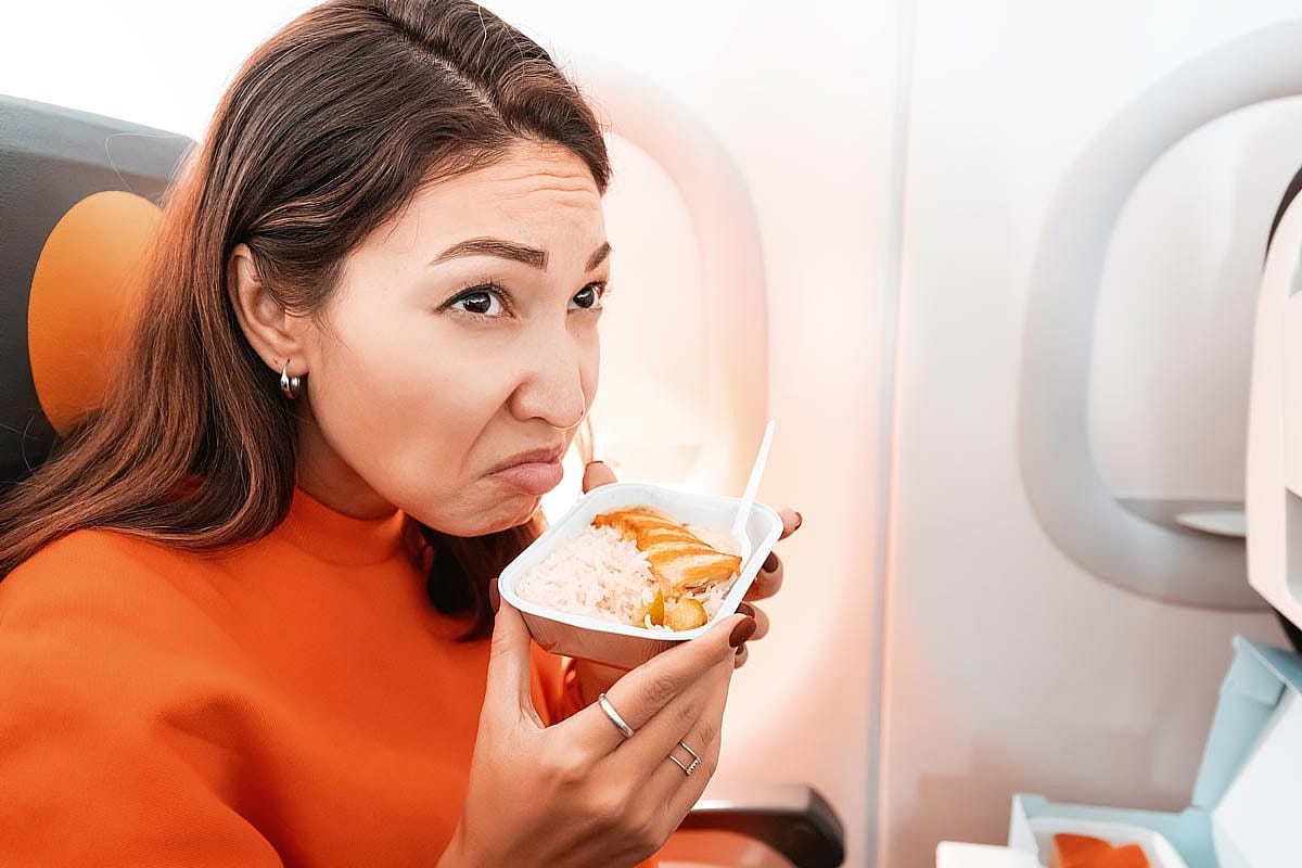 A woman making a bad face while smelling her airline meal.
