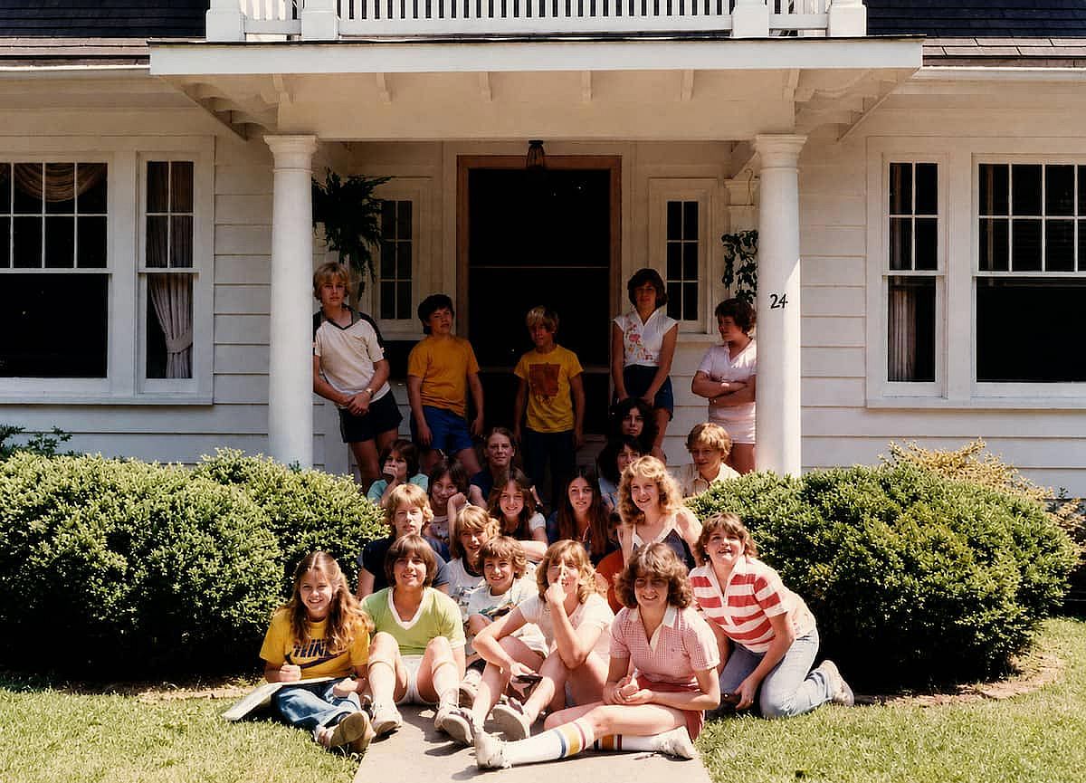 Smiling kids outside a house, during a school field trip in 1980.