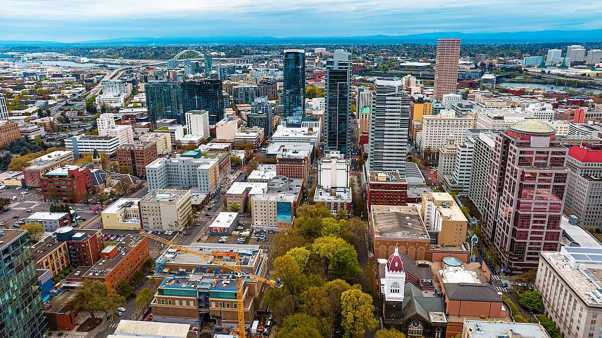 Downtown of Portland, Oregon, the USA with high-rise architecture. Twilight view of the city with mountain silhouettes at backdrop.