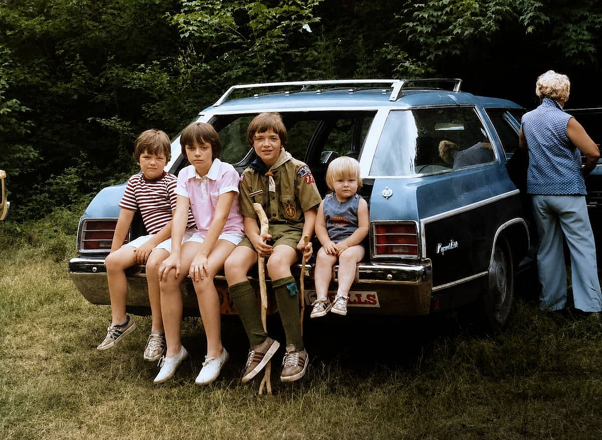 Four siblings sitting in the back of the car during July of 1980.