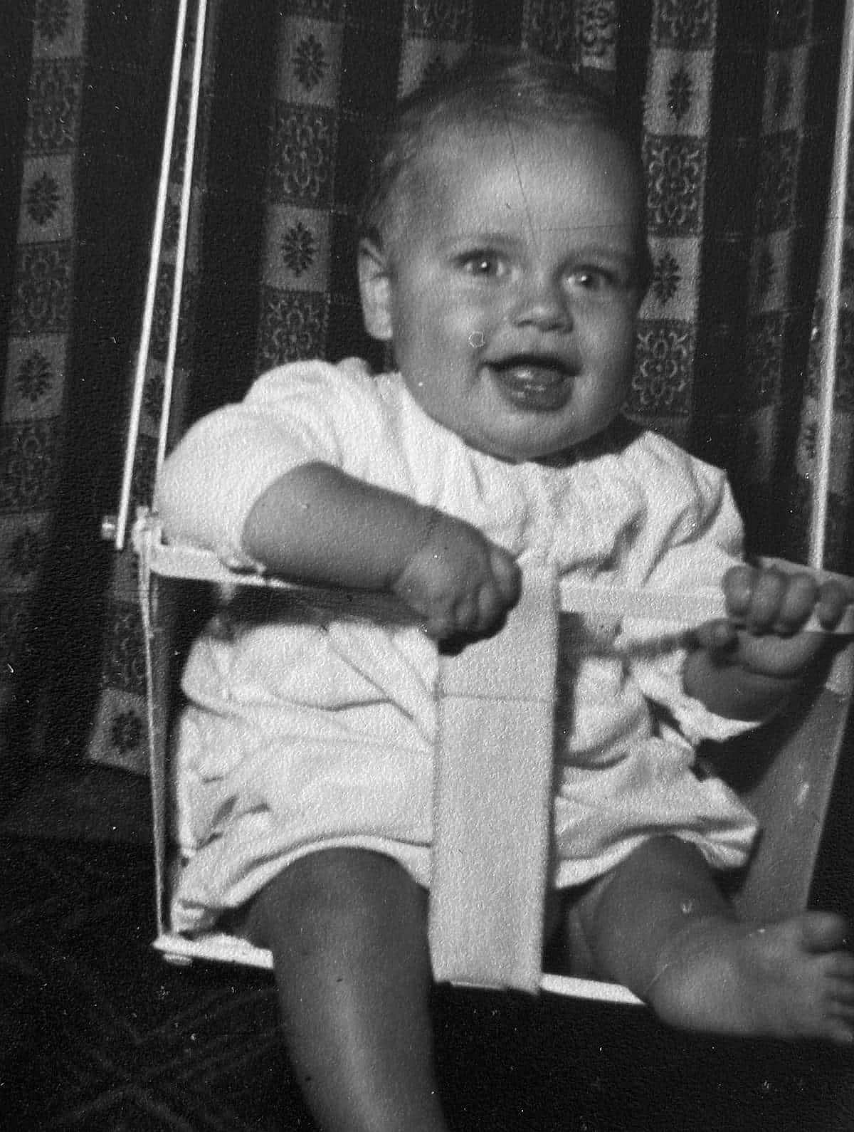 Vintage Black and White photo of a child in a high chair.
