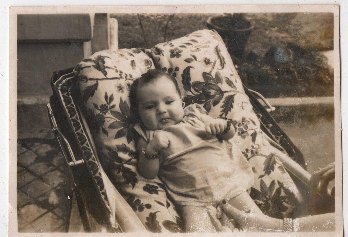 Vintage black and white photo of a baby reclining in a stroller.