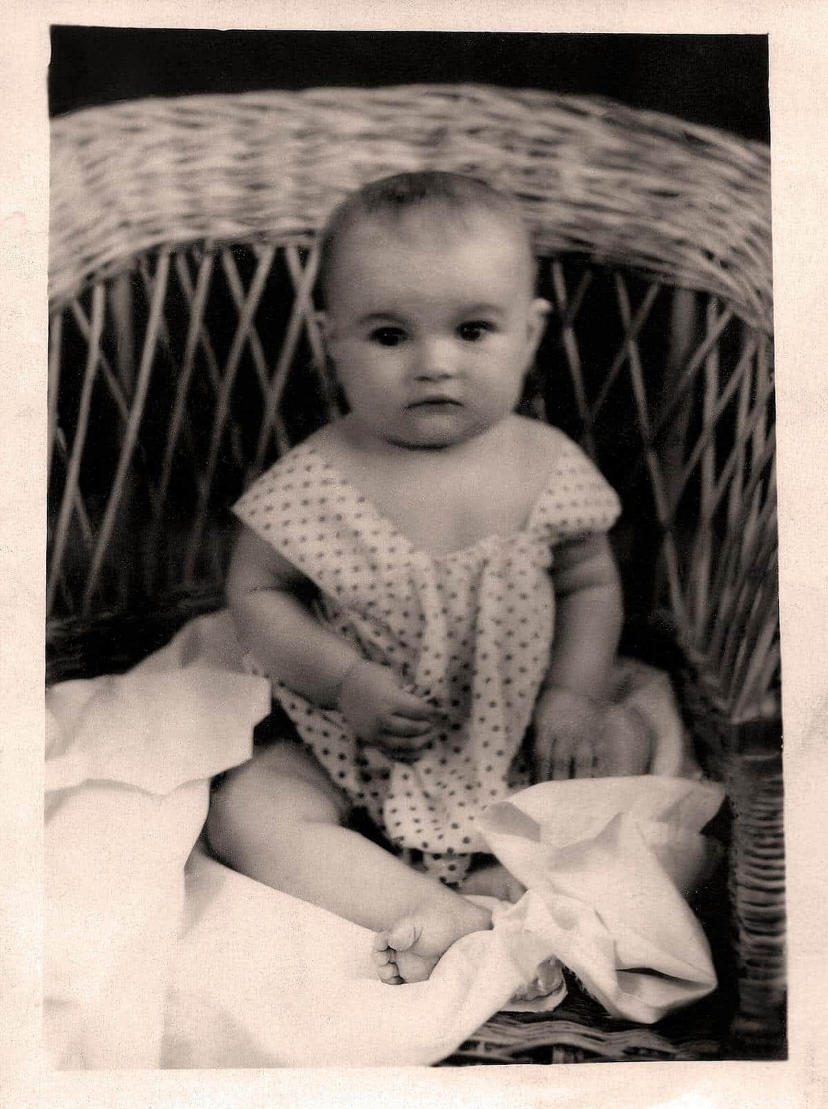 Vintage portrait of a little girl sitting in a playpen. Retro photo from 1946.