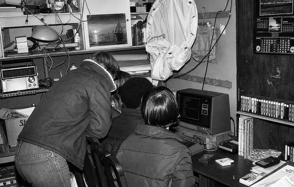 Group of friends playing a game on a computer, in 1980.