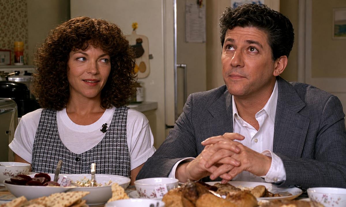 Amy Irving looking at Peter Riegert while sitting on a table during a scene of Crossing Delancy (1988)