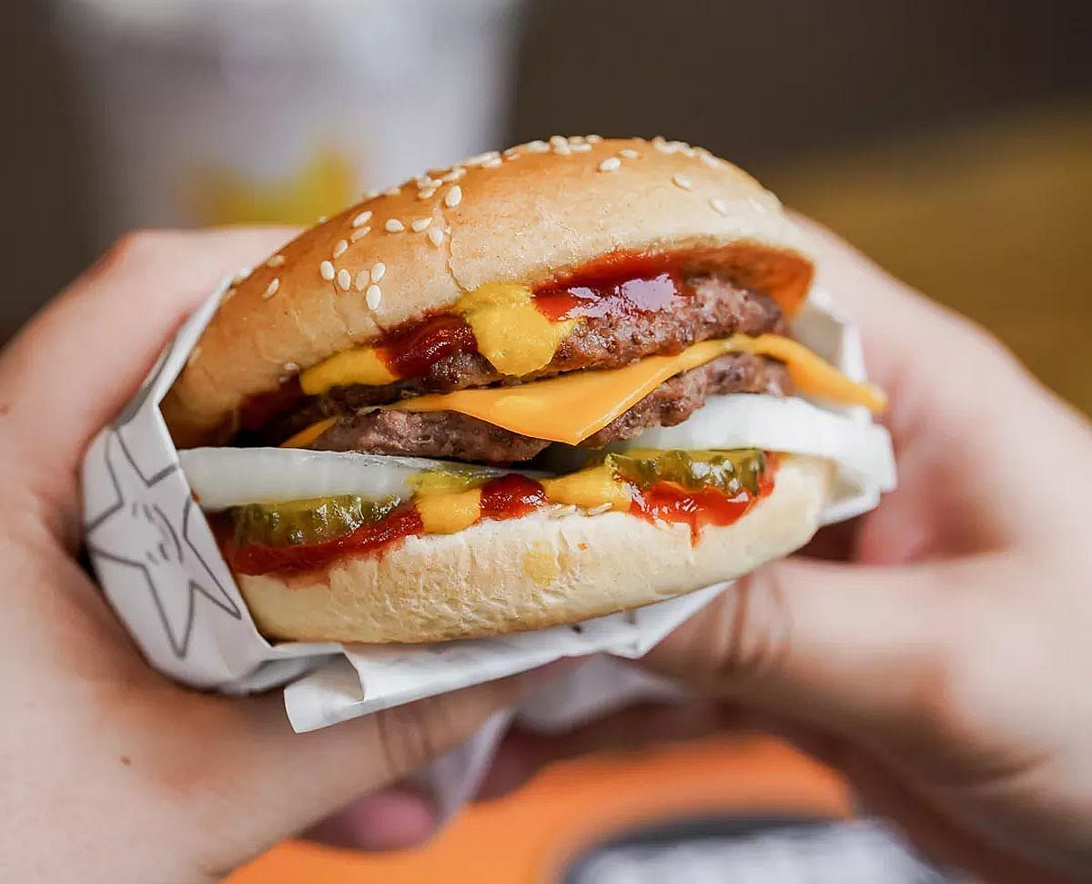A Double Cheeseburger from Carl's Jr. being held by two hands.