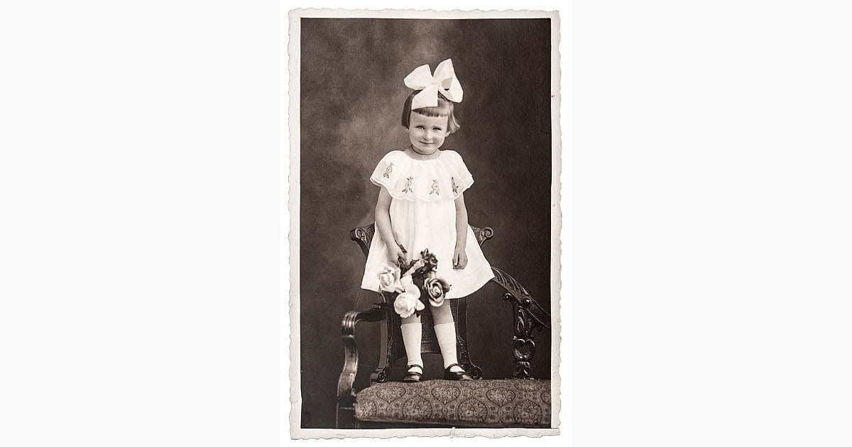 CIRCA 1940: old photo of little girl with flowers in white dress. nostalgic picture, circa 1940.