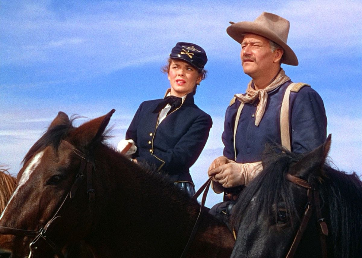 John Wayne and Joanne Dru on horseback.
