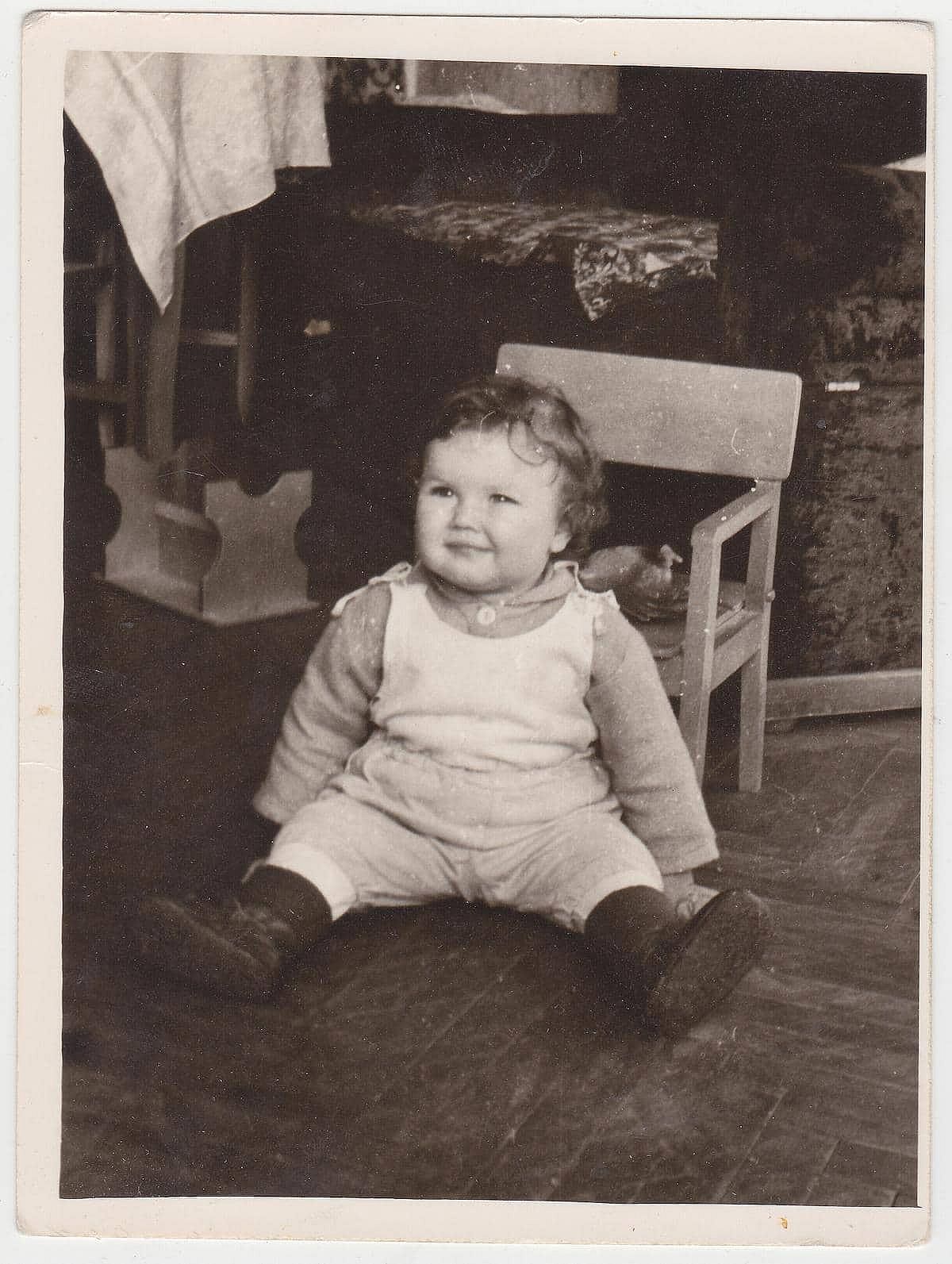 Vintage photograph of a small child sitting on the floor.