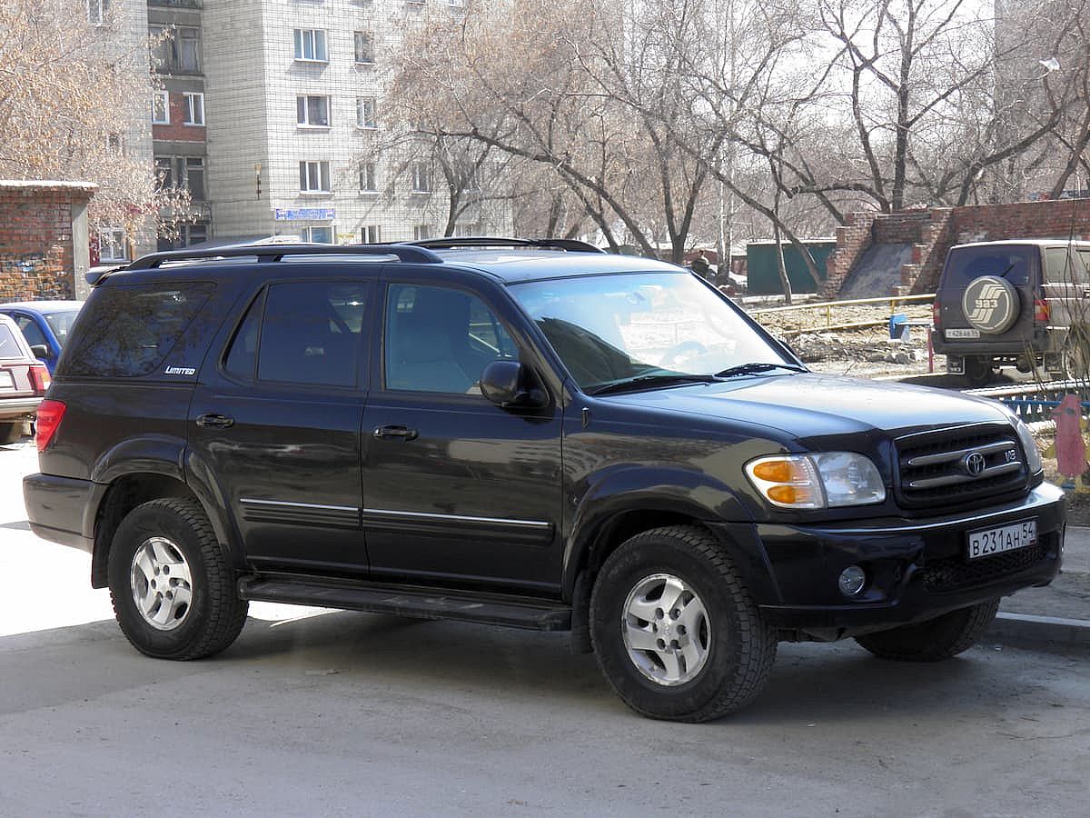 All-wheel drive black metallic color big frame SUV Toyota Sequoia, popular USDM US-spec japanese car crossover exported made in USA on urban street.