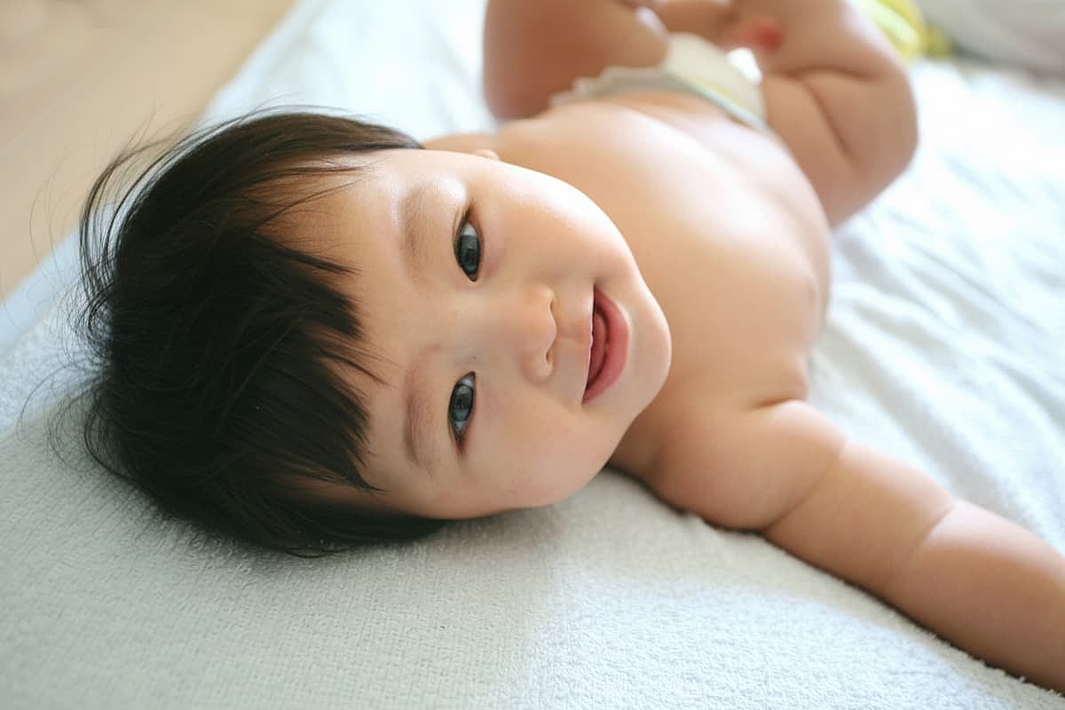 A cute smiling Japanese baby lying down and looking at you Asian infant.