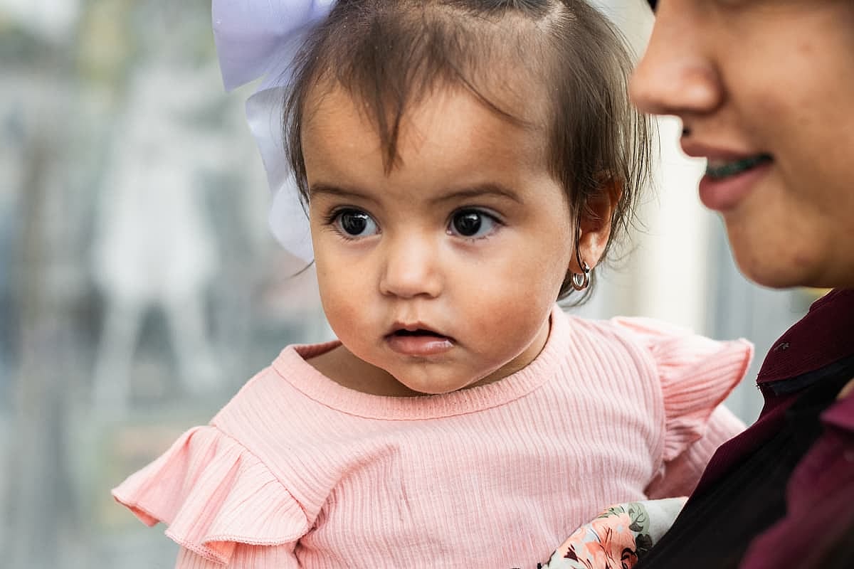 close-up of the face of a beautiful latina baby being carried by her mother
