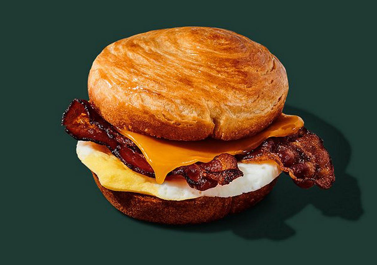 Promo photo of the double-smoked bacon, cheddar & egg sandwich from Starbucks with a green background