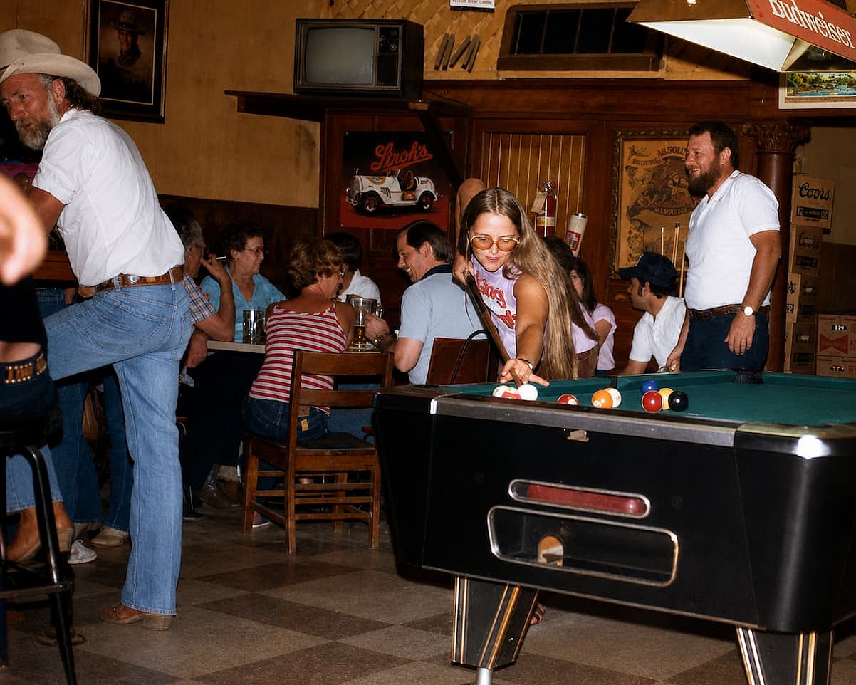Different people enjoying a Friday at a bar playing pool in 1982