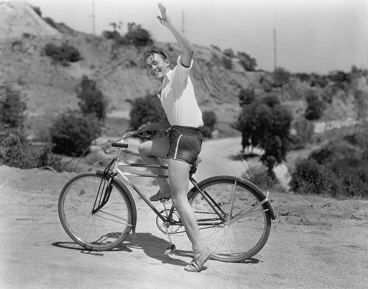 Male bicyclist waving goodbye.