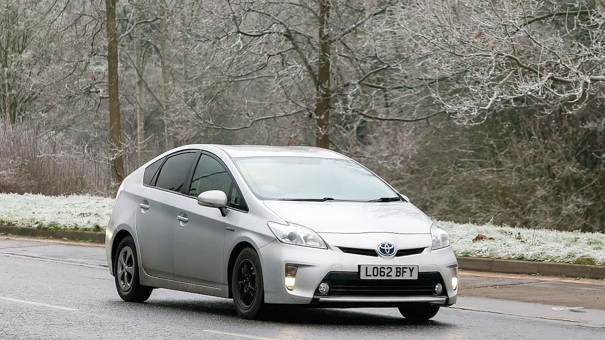 Toyota Prius hybrid electric car driving on a cold, frosty morning.