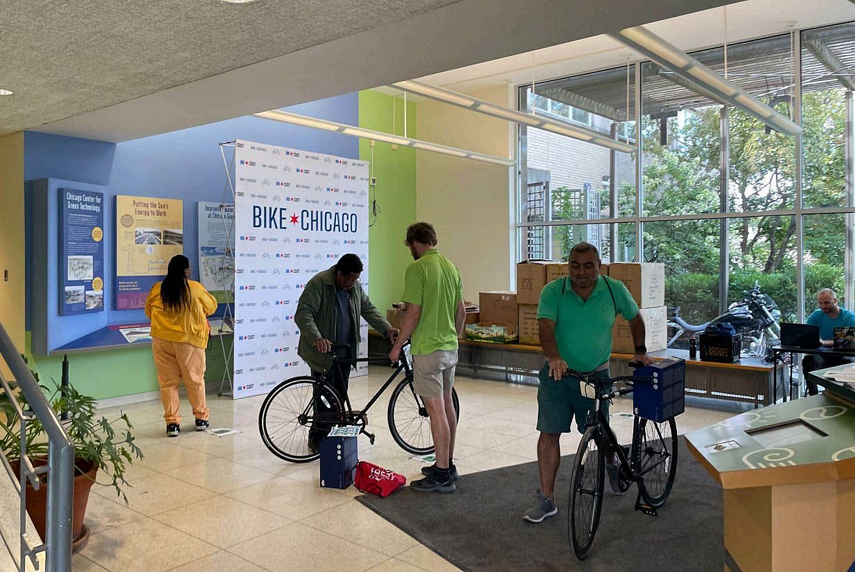 Participants receive bikes and wheel them through a lobby at the Bike Chicago program.
