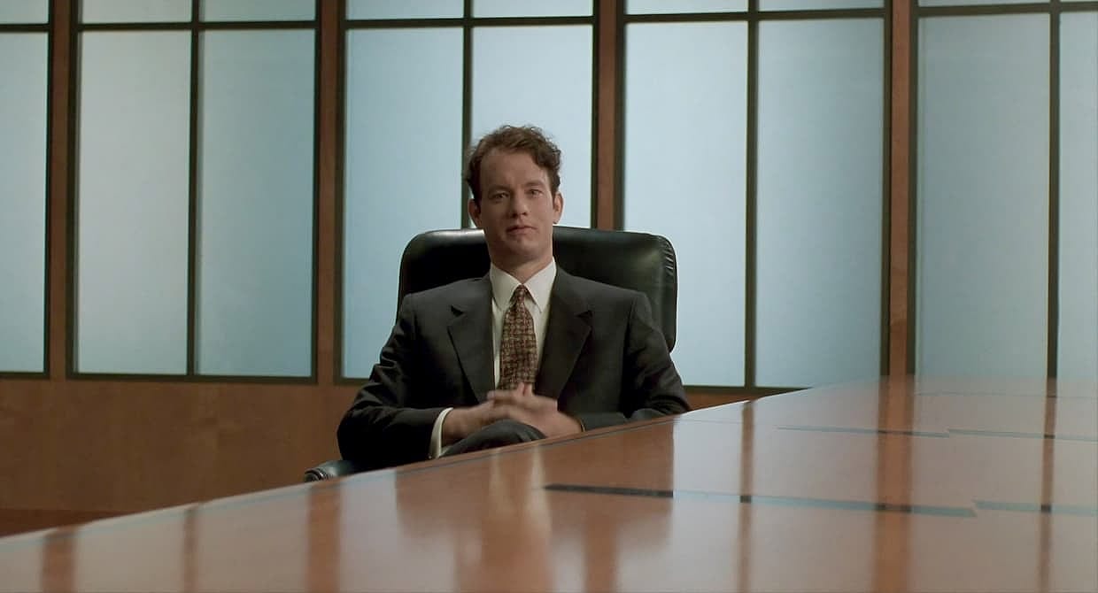 Tom Hanks sitting at a corporate table for a scene of Philadelphia