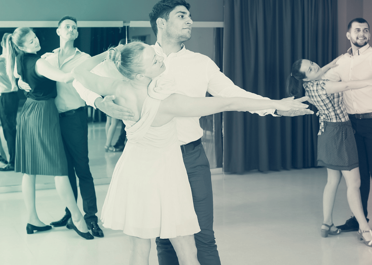Couples practice partner dancing in a ballroom dance studio, performing dramatic Latin dance holds and dips.