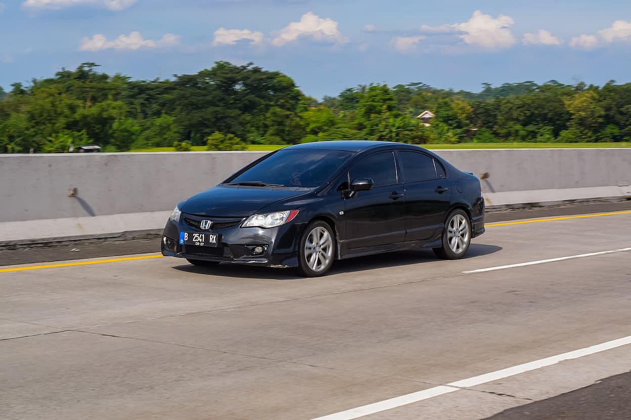 Black Honda Civic FD1 sedan driving fast on a highway.
