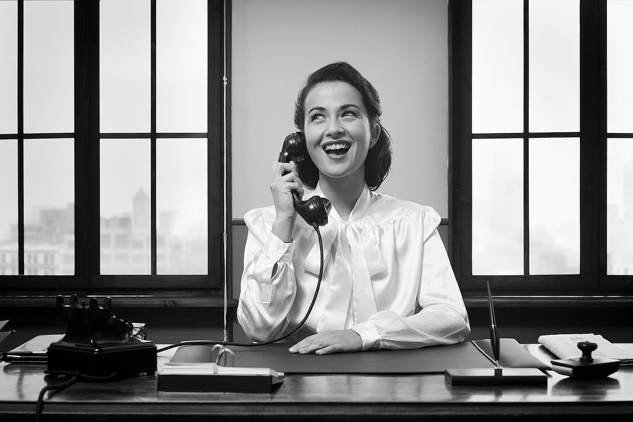 Smiling vintage receptionist working at office desk and smiling