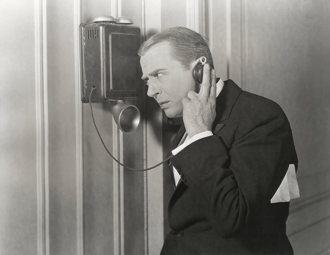 A black and white photo of a man on a telephone