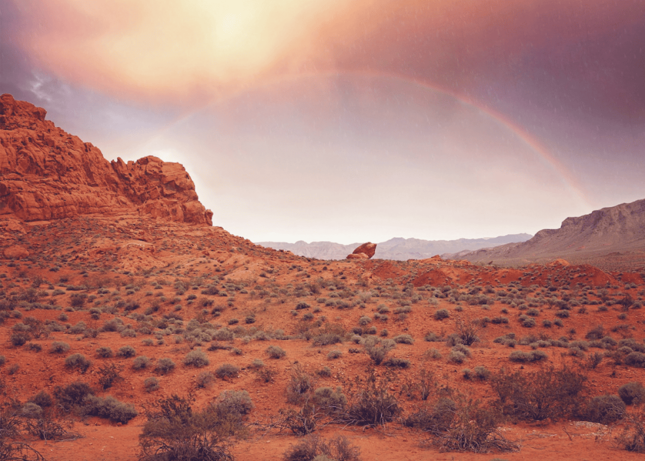 Red rock formations with a rainbow above
