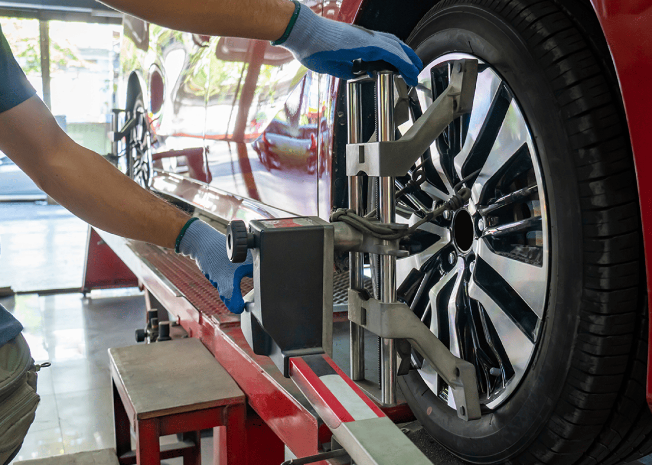 A mechanic checking tire alignment on a car.