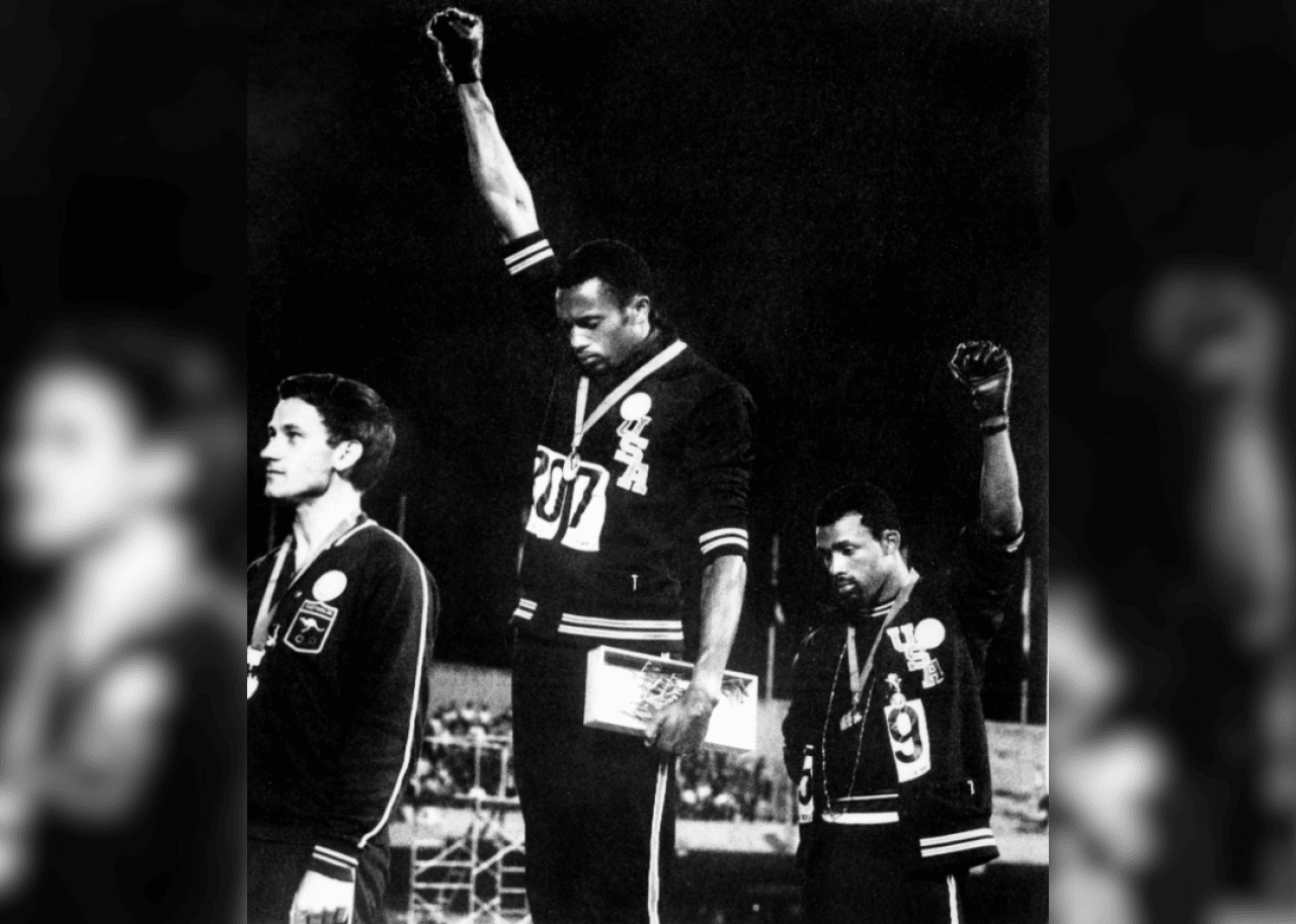 Olympic medalists with raised fists on podium.