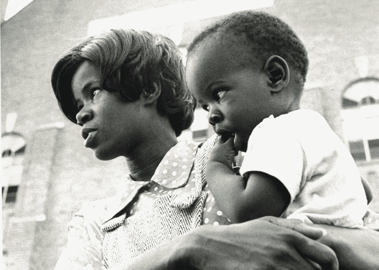 A mother and child watch the Unity March at a Juneteenth celebration.