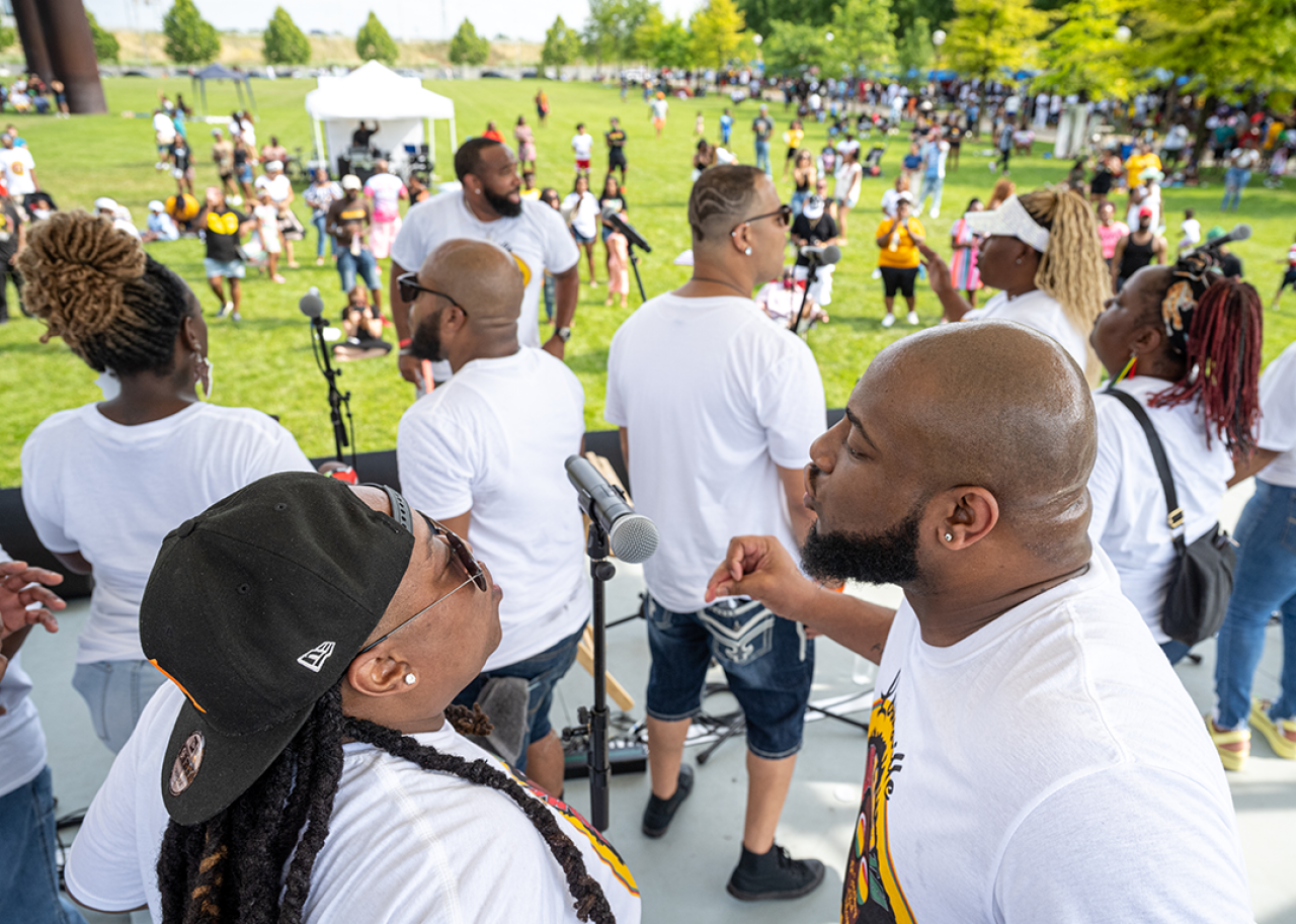 Two choir singers share a microphone during a performance at the Louisville Juneteenth Festival.