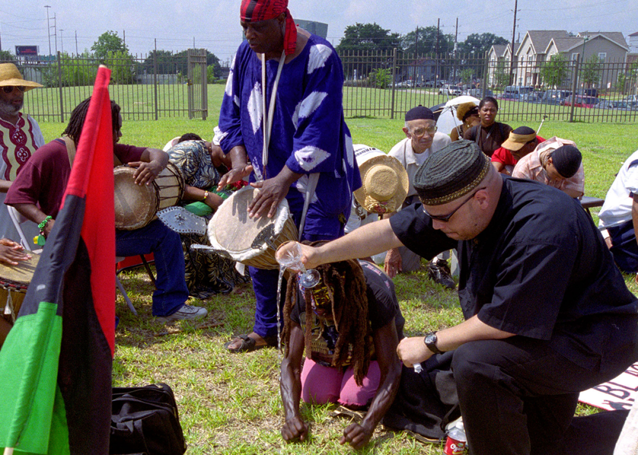 A man pours a glass of water on the ground as he conducts a Pouring of Libation Ceremony.