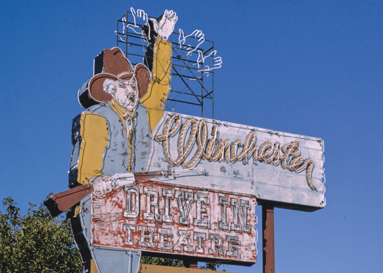 Winchester Drive-In neon cowboy sign during daytime.