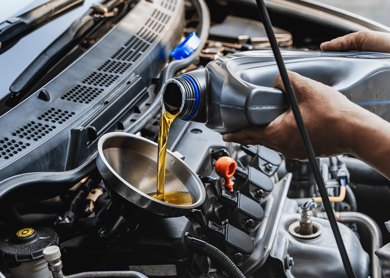 A mechanic pouring engine oil into a vehicle.