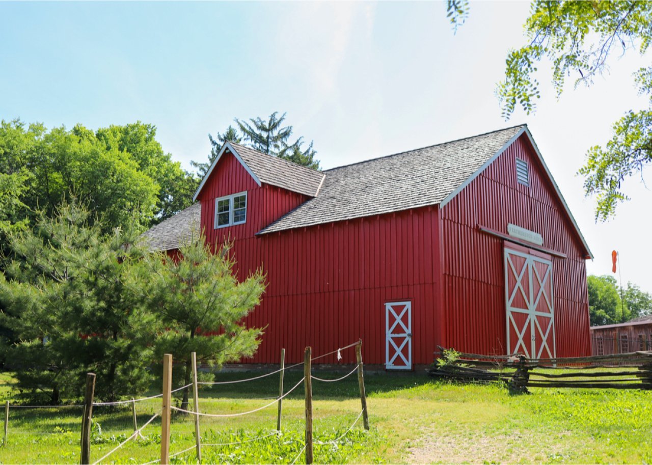Red barn in a green field on summer day.