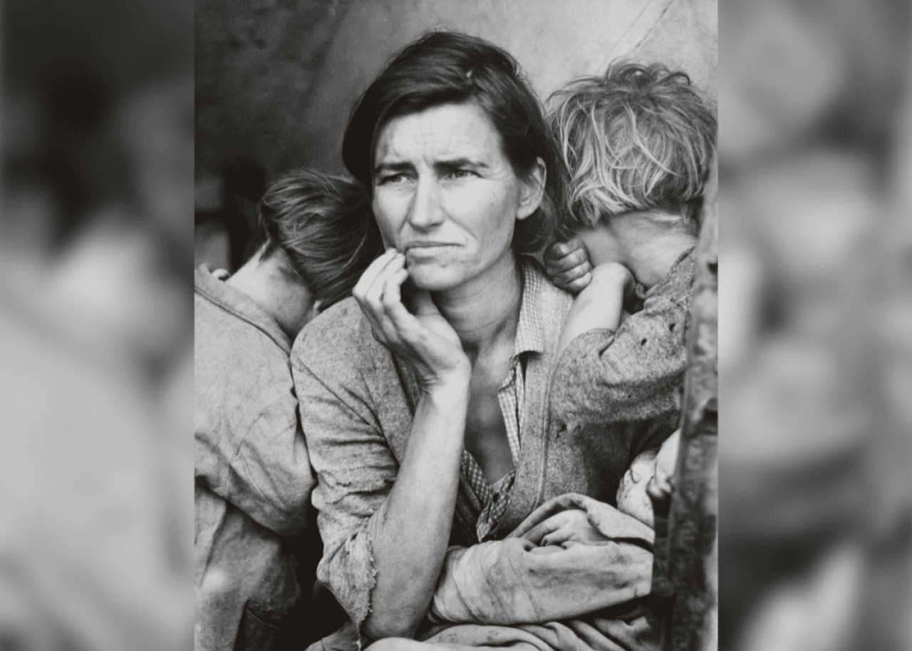 A woman with her hand to her face holding an infant with young two children facing away from the camera.