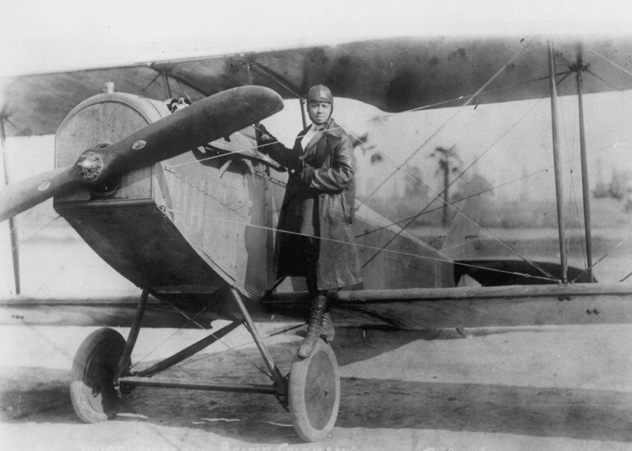 Bessie Coleman poses beside her bi-plane.