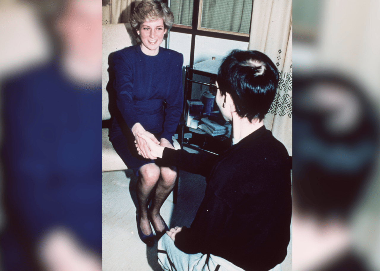 Princess Diana shaking hands with man in hospital.