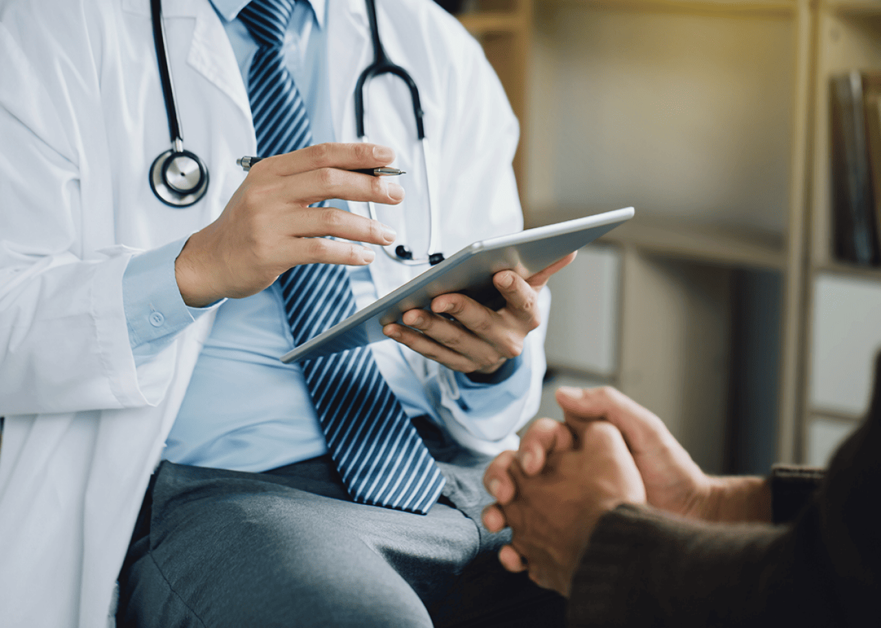Doctor holding a tablet, speaking with patient.