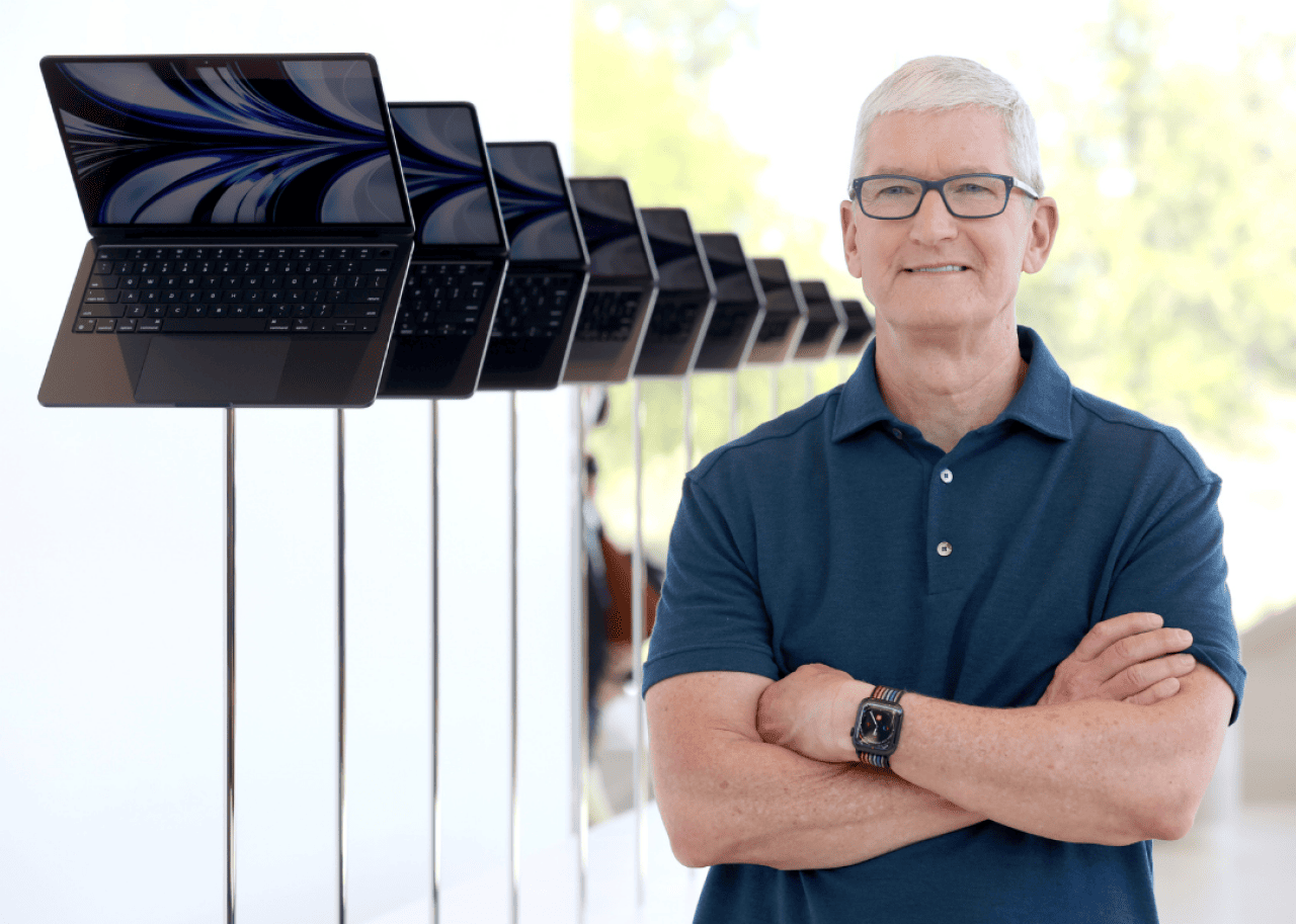 Tim Cook Tim Cook stands next to a display of laptops during the WWDC22.