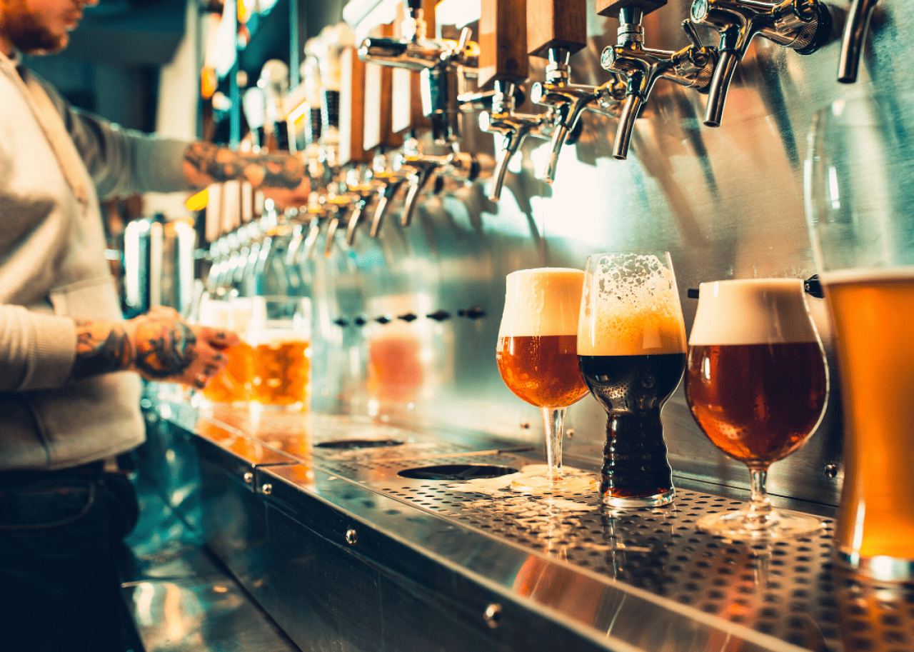 A beertender fills glasses of beer from several taps.