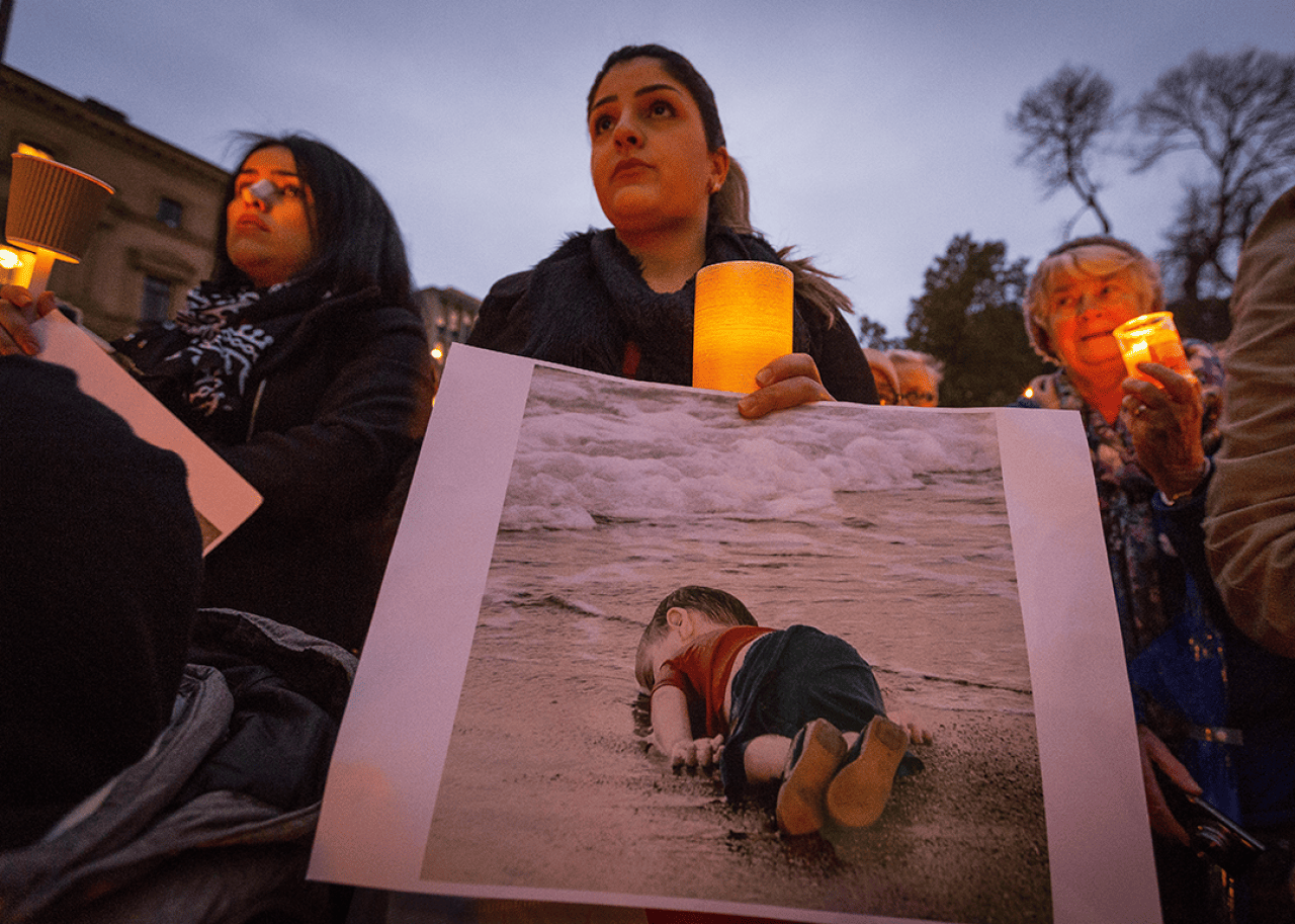 A woman holds a picture during the a vigil in rememberence of Aylan Kurdi.