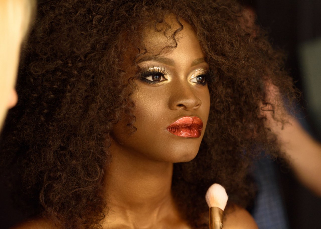 Woman wearing dramatic gold eye makeup and metallic lipstick.