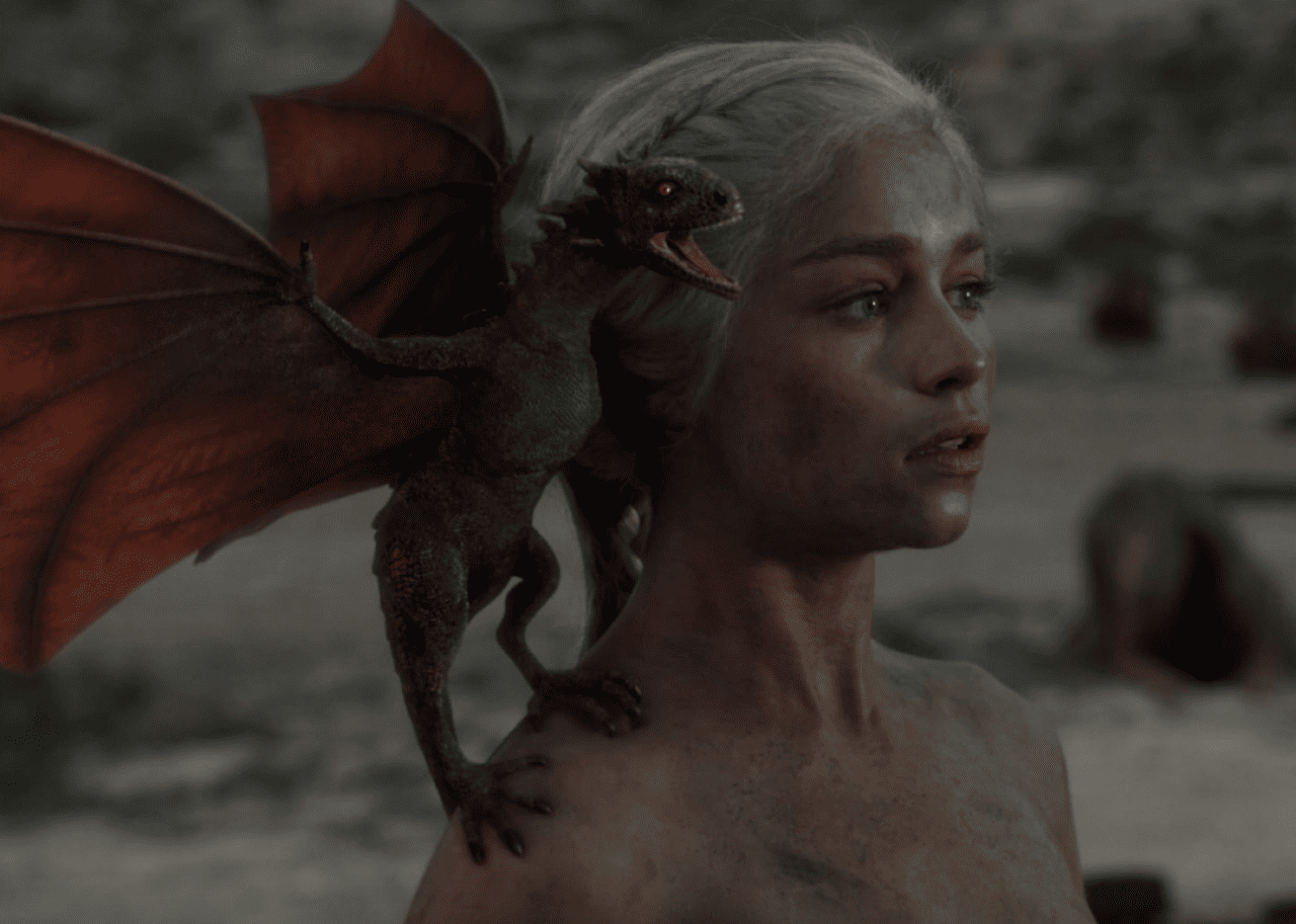 Emilia Clarke with a baby dragon on her shoulder in a scene from
