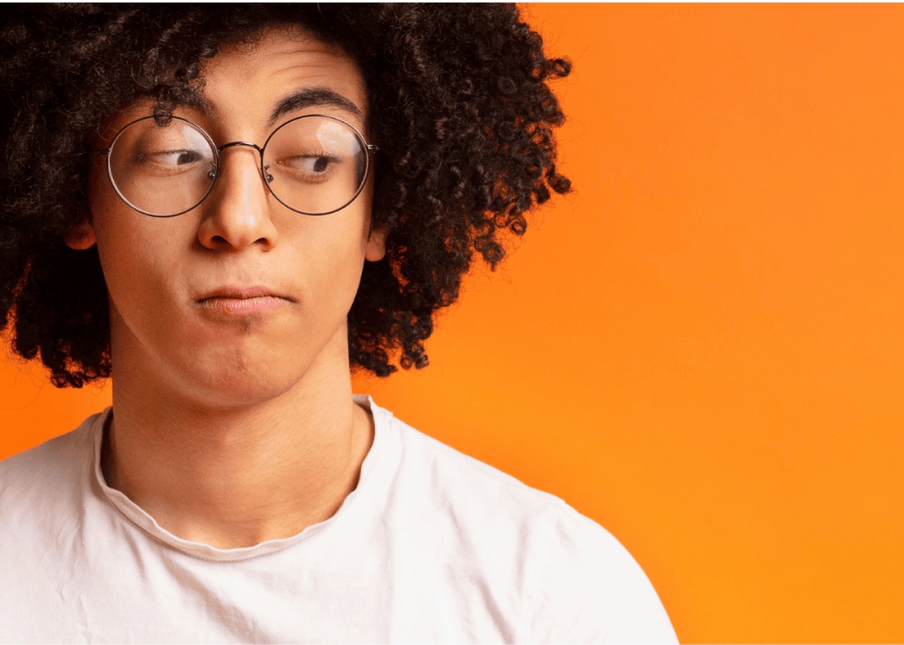 Young man in front of a an orange background giving side eye.