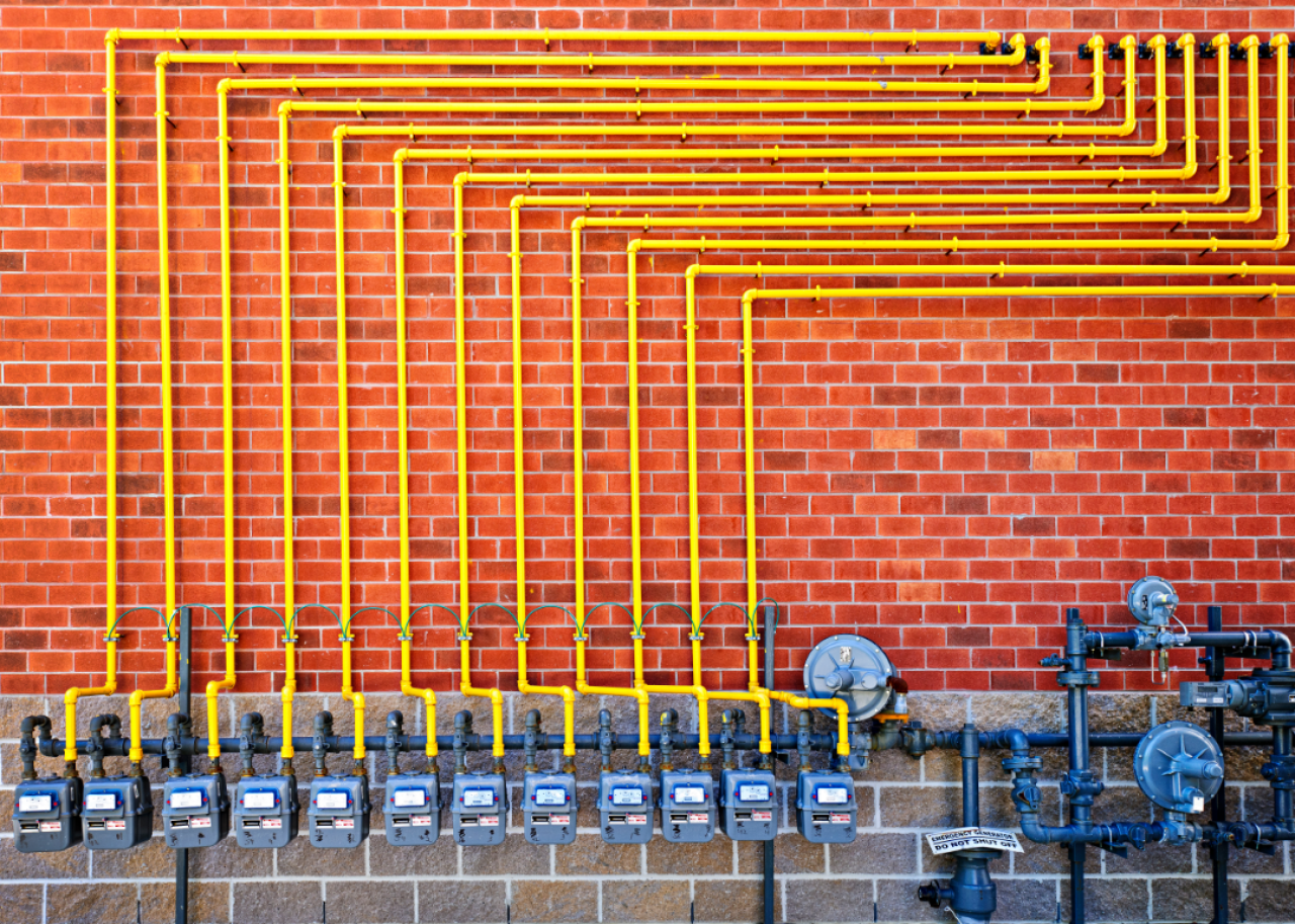row of residential gas meters on a brick wall