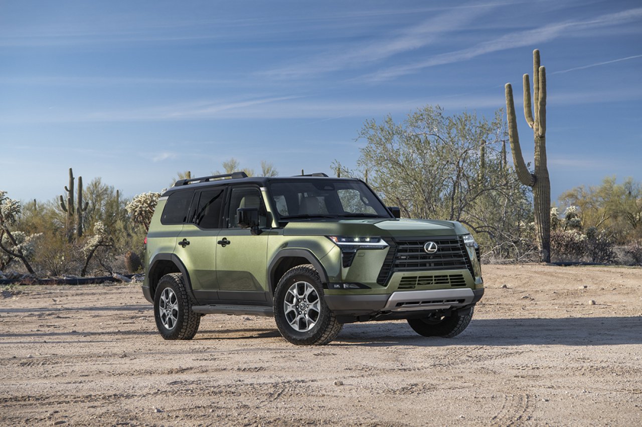 Green Lexus GX parked in desert with Saguaro cactus in background.