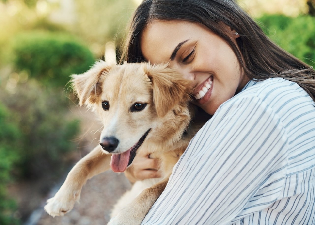 Woman smiling while holding her pet dog.