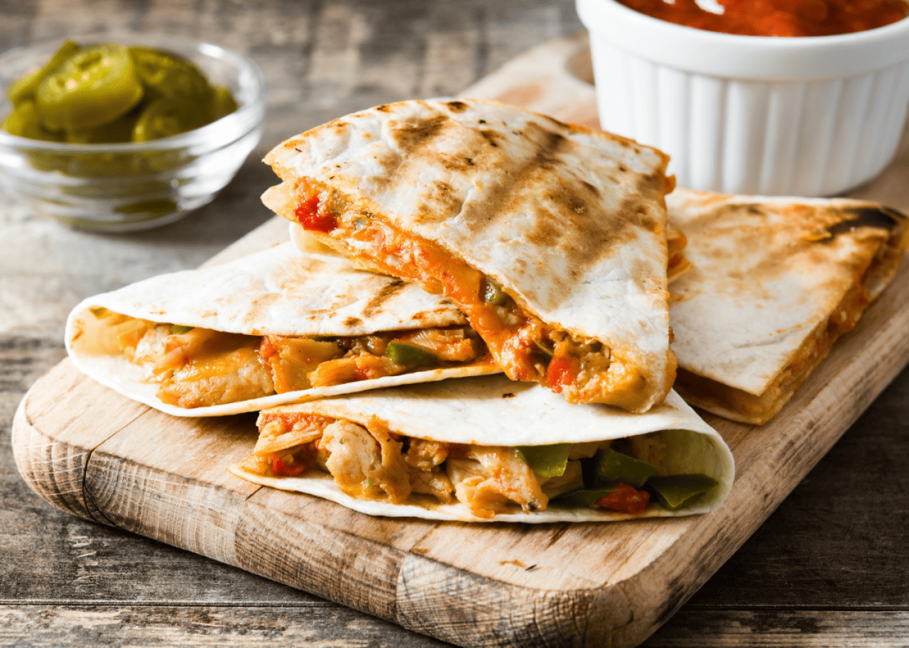 Mexican quesadilla with chicken, cheese and peppers on a wooden table.