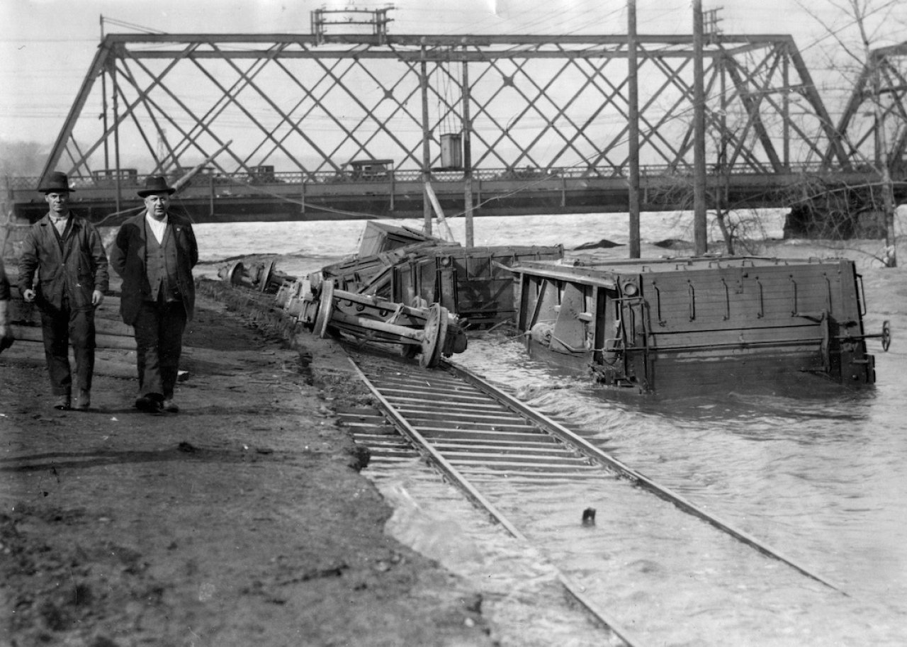 Men travel beside trains sunken underwater after a hurricane.